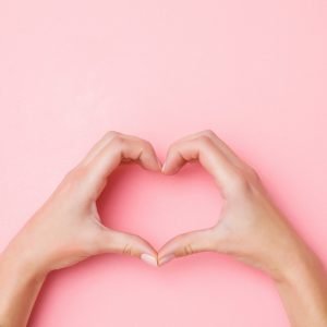 Pink background with hands forming heart shape