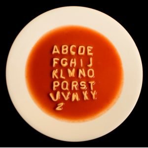 Alphabet soup in white bowl on dark background