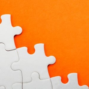 Orange background with white puzzle pieces in bottom left corner